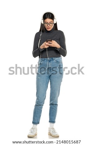 Young woman using phone for search and listening to music on white background.