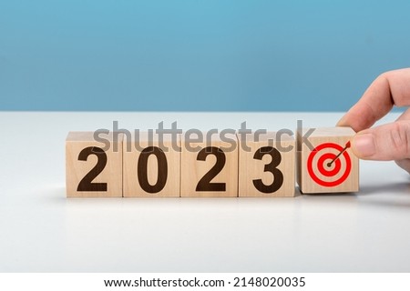 2023 goal. hand putting wooden cubes 2023 with goal icon on table and blue background, copy space. Start new year 2023 with goal plan, goal concept, action plan, strategy, new year business vision.