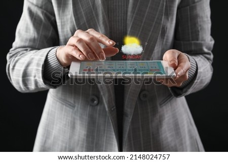 Young woman with tablet computer using weather forecast application on dark background, closeup Royalty-Free Stock Photo #2148024757