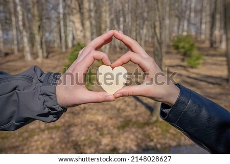 a couple in love holds a heart with their fingers, a symbol of love and happiness