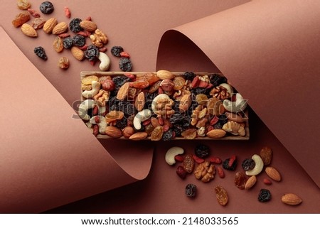 The mix of dried fruits and berries on a brown background. Presented raisins, walnuts, hazelnuts, cashews, pecans, and almonds. Top view. Royalty-Free Stock Photo #2148033565