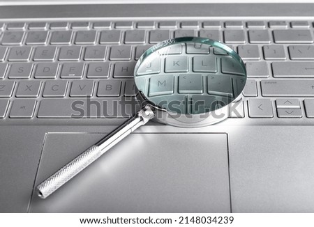 Magnifying glass on laptop keyboard. Information search concept. Digital databases study. Audit conducting using computer. High quality photo