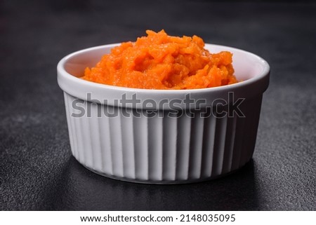 Pumpkin carrot baby puree in bowl on a dark background, top view. Fresh orange squash vegetable pumpkin carrot puree Royalty-Free Stock Photo #2148035095