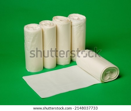 Five rolls of biodegradable eco plastic white garbage bags on green background. New unused rolls of garbage bags for home use. Zero waste lifestyle concept. Advertising banner. Close up. Royalty-Free Stock Photo #2148037733