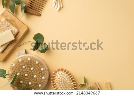 Top view photo of spa accessories anti-cellulite washcloth soap on wooden stand hairbrushes cotton buds clothespins and eucalyptus on isolated beige background with copyspace