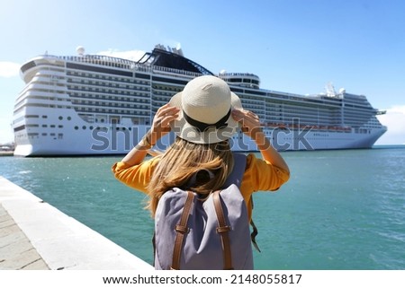 Tourist girl with backpack and hat standing in front of big cruise liner Royalty-Free Stock Photo #2148055817