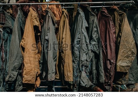 Collection of wax jackets on hangers in the shop. Many vintage men's jackets. Background and closeup texture of wax jackets.