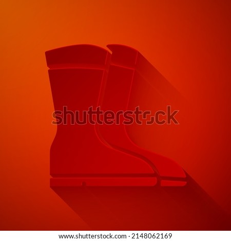 Paper cut Fishing boots icon isolated on red background. Waterproof rubber boot. Gumboots for rainy weather, fishing, hunter, gardening. Paper art style. Vector