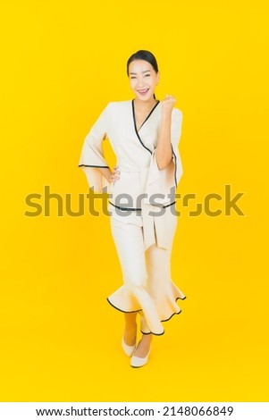 Portrait beautiful young business asian woman with smile and action yellow background