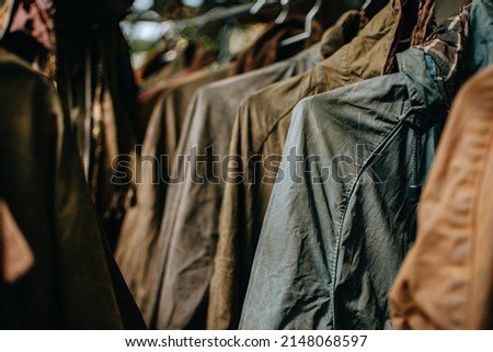 Iconic wax jacket showing the coats detail and texture. Men's vintage wax jackets on hangers outdoors.