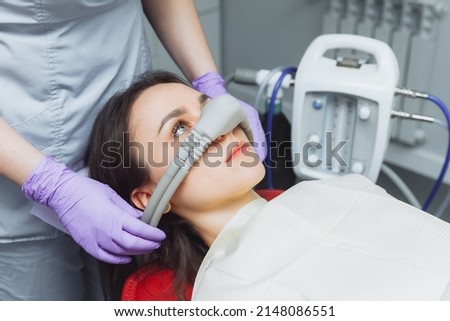 dentist puts inhalation sedative mask on his patient. Royalty-Free Stock Photo #2148086551