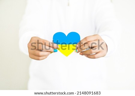 The concept of love for Ukraine. heart in the colors of the flag of Ukraine in female hands on a white background.