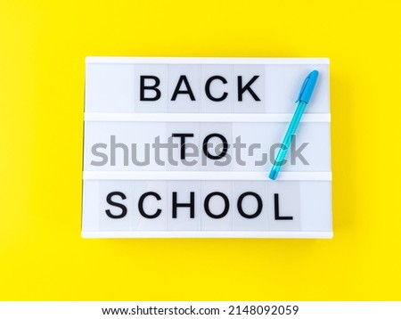 White lightbox with back to school text on yellow background with blue pen. Starting a new school year concept
