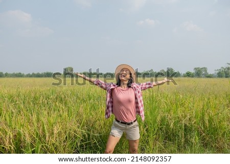 Young woman walking in rice field in thailand. Travelling to clean places of Earth and discovering beauty of nature. Young woman traveler with hat standing.