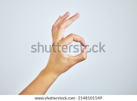 Youre doing just fine. Studio shot of a woman making an a-okay sign with her hand against a grey background.