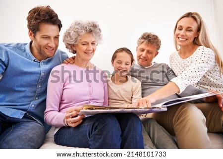This is my favorite picture of us. Shot of a happy multi generation family looking through a photo album together.