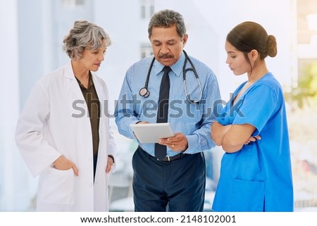 Going over some medical records. Shot of three healthcare professionals looking over medical records on a tablet.