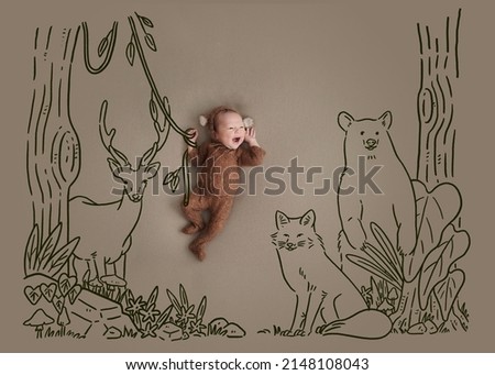 Little baby with drawing (doodle). Newborn wearing monkey bodysuit. Tarzan baby hanging vines in the forest among the herds are bear, deer and fox.