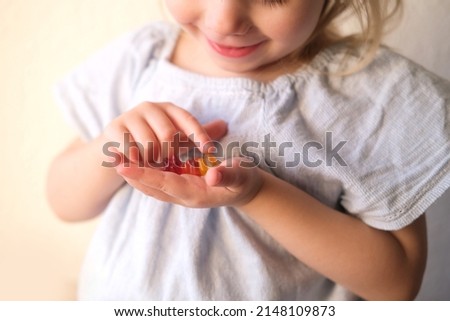 small child, blonde girl 3 years old wants to eat gelatinous sweets, gummy bear, kid has a good appetite, happy childhood, balanced diet, sweet life, unhealthy food, halal food Royalty-Free Stock Photo #2148109873