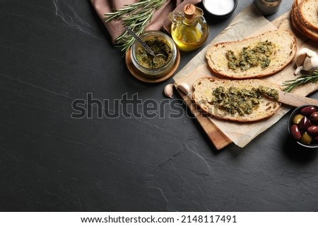 Tasty bruschettas with pesto on black table, flat lay. Space for text