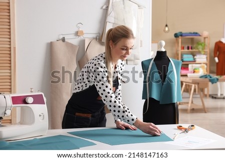 Dressmaker marking fabric with chalk in workshop