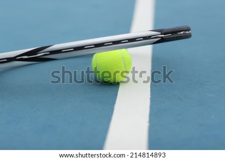 Yellow Tennis Ball and Racket on the blue court