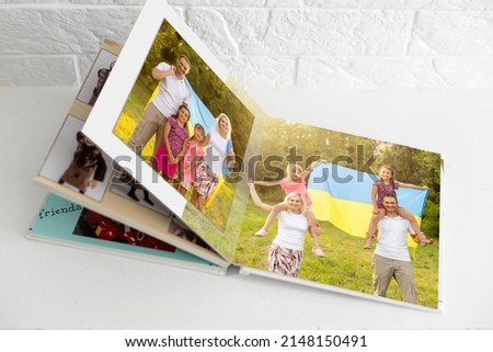 Family photos archive saved in brightly designed photo book; bright summer memories placed in the photobook. family with flag of ukraine