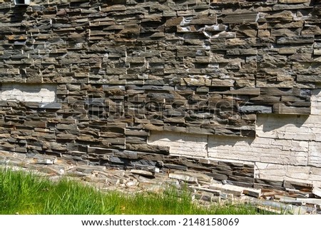 damaged Dark Stone wall Texture background in the garden, weathered and untreated stone texture, decorative stone tiles, cladding wall damaged by time