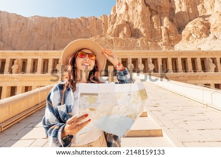 A girl tourist and traveler with a map is exploring the sights of the ancient city of Thebes or modern Luxor standing near the temple of Pharaoh's queen Hatshepsut Royalty-Free Stock Photo #2148159133