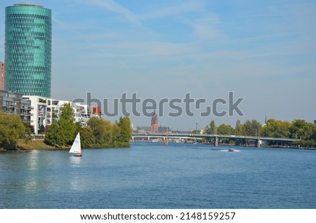 View over the Main river in Frankfurt with a sailboat and some bridges. In the background the tower of the Kaiserdom St. Bartholomäus