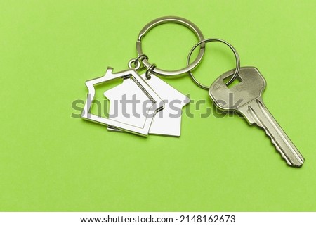 The concept of mortgage and rental housing and real estate. Mortgage credit lending. Keychain in the shape of a house with a key on a light green background