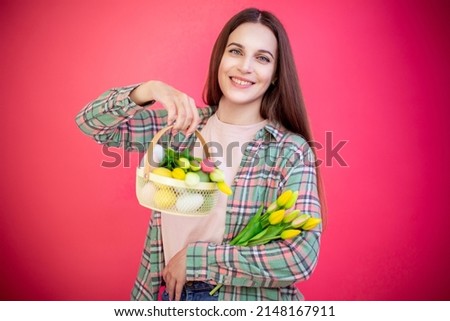 Happy young woman enjoy easter eggs and bouquet of tulips on pink background.