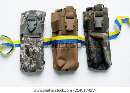 Top view of blue and yellow ribbon on military bags on white background