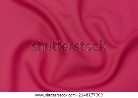 Close-up texture of natural red or pink fabric or cloth in same color. Fabric texture of natural cotton, silk or wool, or linen textile material. Red and orange canvas background. Royalty-Free Stock Photo #2148177909