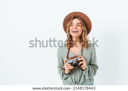 Happy young female freelance photographer holding her vintage camera smiling while looking away