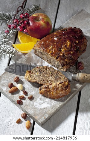 Christmas fruitcake with nuts and fruits and christmas decorations on wooden board