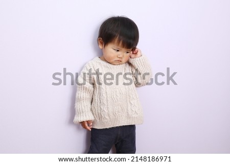 A picture of a young girl with a sad expression wearing a white sweater.