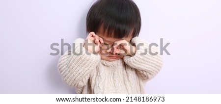 A picture of a young girl with a sad expression wearing a white sweater.