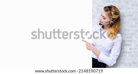 Call Center Service concept - customer support or sales agent. Businesswoman, caller, phone operator pointing finger at empty white signboard. Helping, answering, consulting chat. White bricks wall.