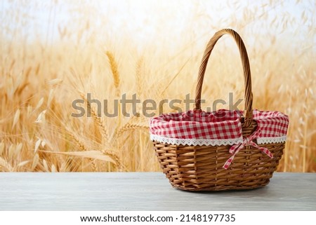 Empty picnic basket on wooden white table over wheat field blurred background. Shavuot holiday mock up for design and product display Royalty-Free Stock Photo #2148197735
