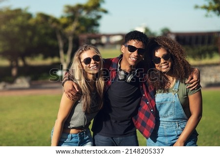 Sunglasses on. Portrait of a group of cheerful young friends posing for a photo together while wearing sunglasses outside in a park.