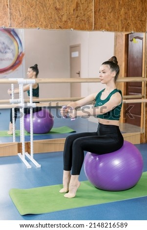 Girl in green topic doing exercises with fit ball