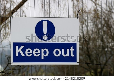 Keep out sign hanging on a building site perimeter fence