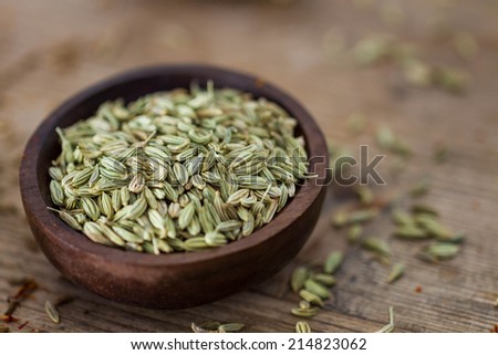 Fennel seeds in a small wooden bowl on an old wooden table. Royalty-Free Stock Photo #214823062