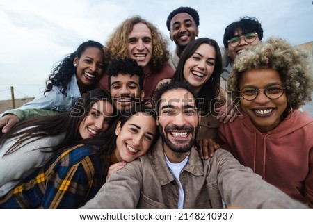 Big group portrait of diverse young people together outdoors - Multiracial happy millennial male and female friends having fun together - Unity and friendship concept - Focus on man in the center Royalty-Free Stock Photo #2148240937