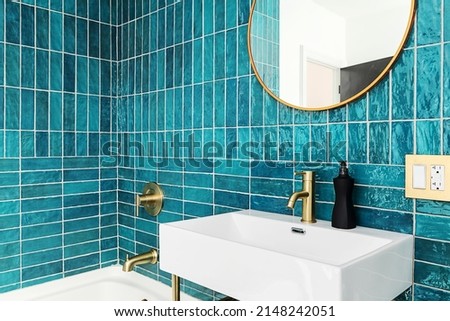 Modern and Vibrant Bathroom. Blue and Green Tile bathroom with gold fixtures and mirror. Royalty-Free Stock Photo #2148242051