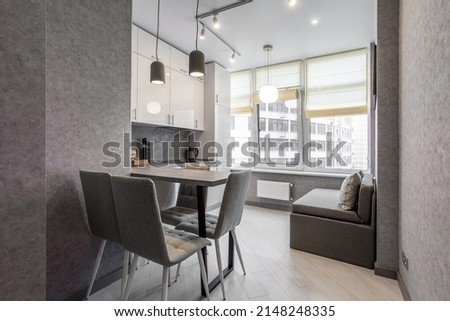 Clean kitchen in a small cozy contemporary studio apartment. Table and chairs in the foreground. Built in household appliance Royalty-Free Stock Photo #2148248335