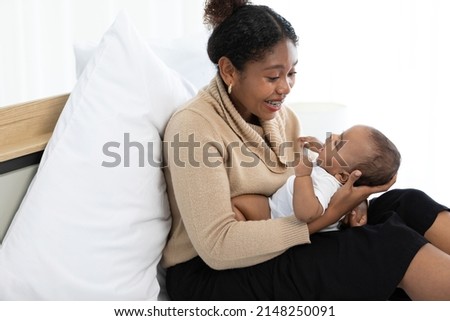 African young mother playing with her adorable baby on bed