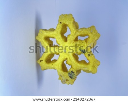 A traditional yellow Kokis sweet on a white background
