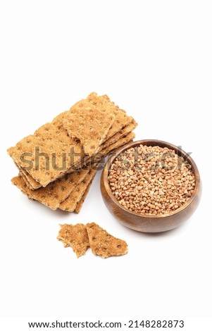 Stack of buckwheat crispbread and grain in a wooden bowl isolated on white background. Healthy snack